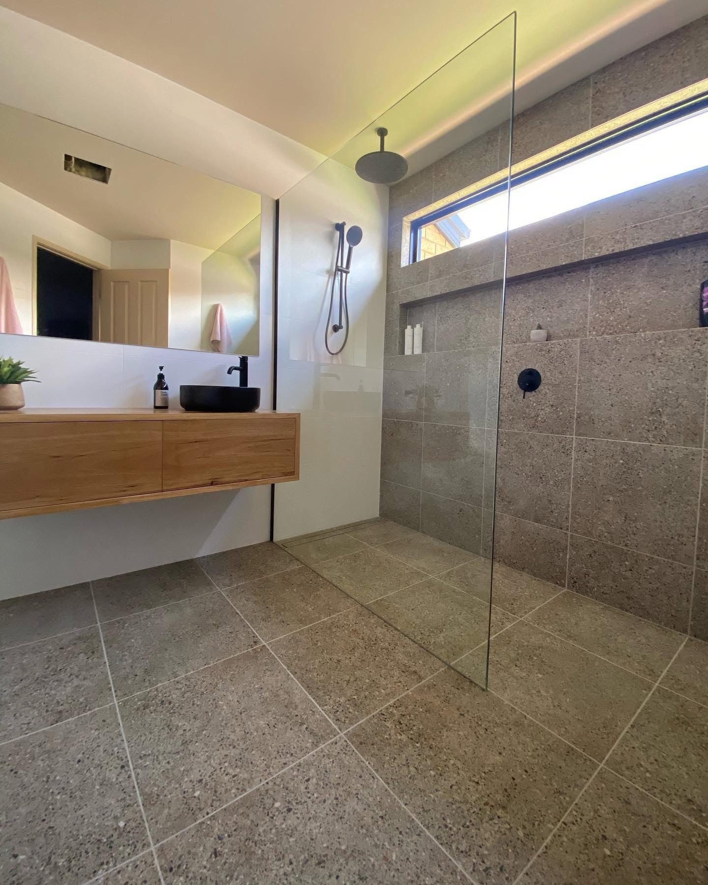 Minimalist bathroom with black tapware and natural timber vanity